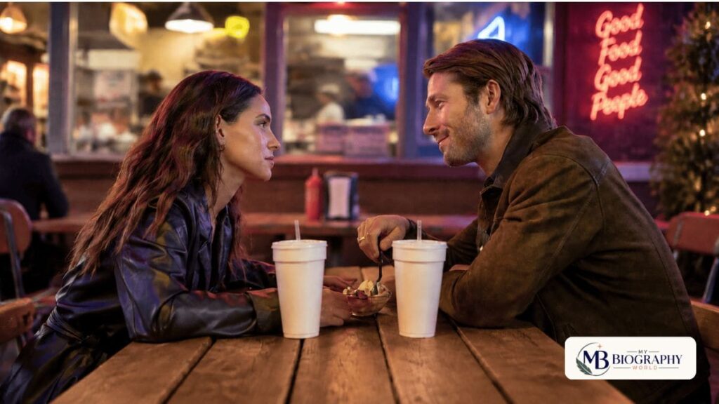 Adria Arjona and her co-star sitting together at a restaurant scene, featured in a My Biography World biography article.